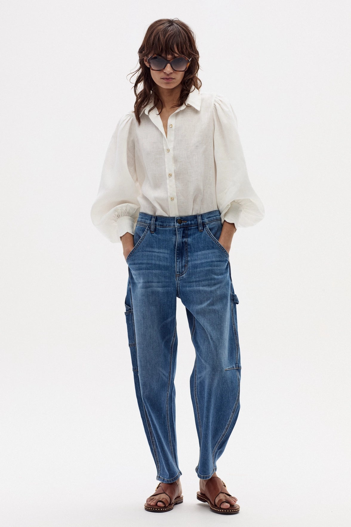Woman wearing a white blouse and blue jeans on a white background